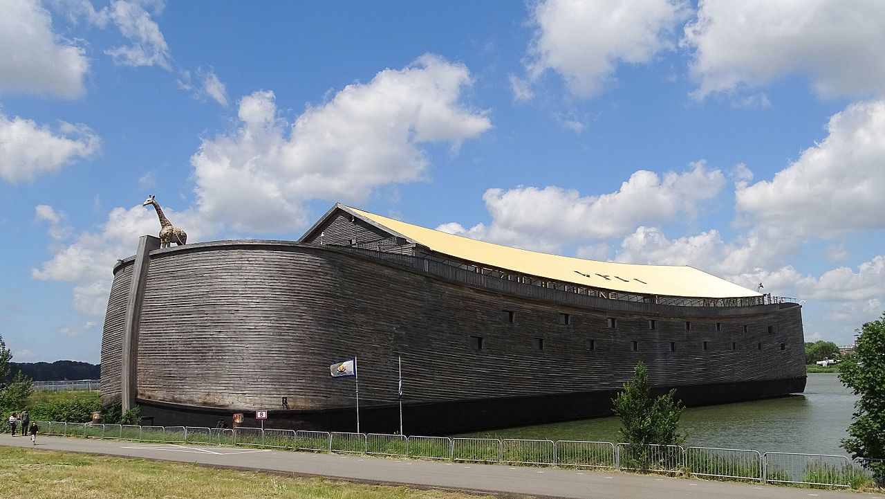 A full-scale wooden ark replica moored at the water's edge