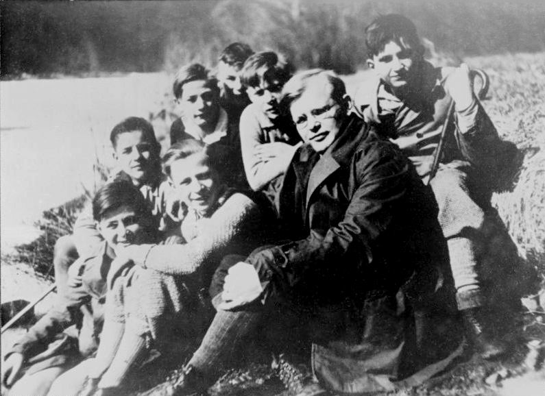 Black-and-white photo of Bonhoeffer seated outdoors among young people