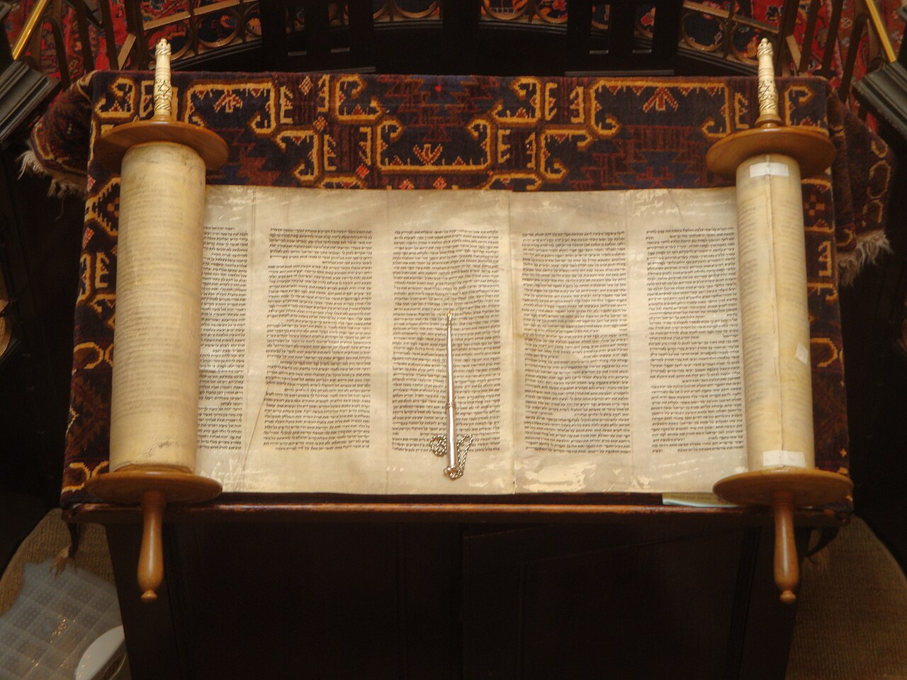 An open Hebrew Torah scroll rolled on two wooden staves