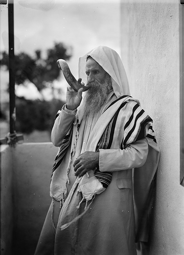 An old photograph of a Jewish man blowing a shofar
