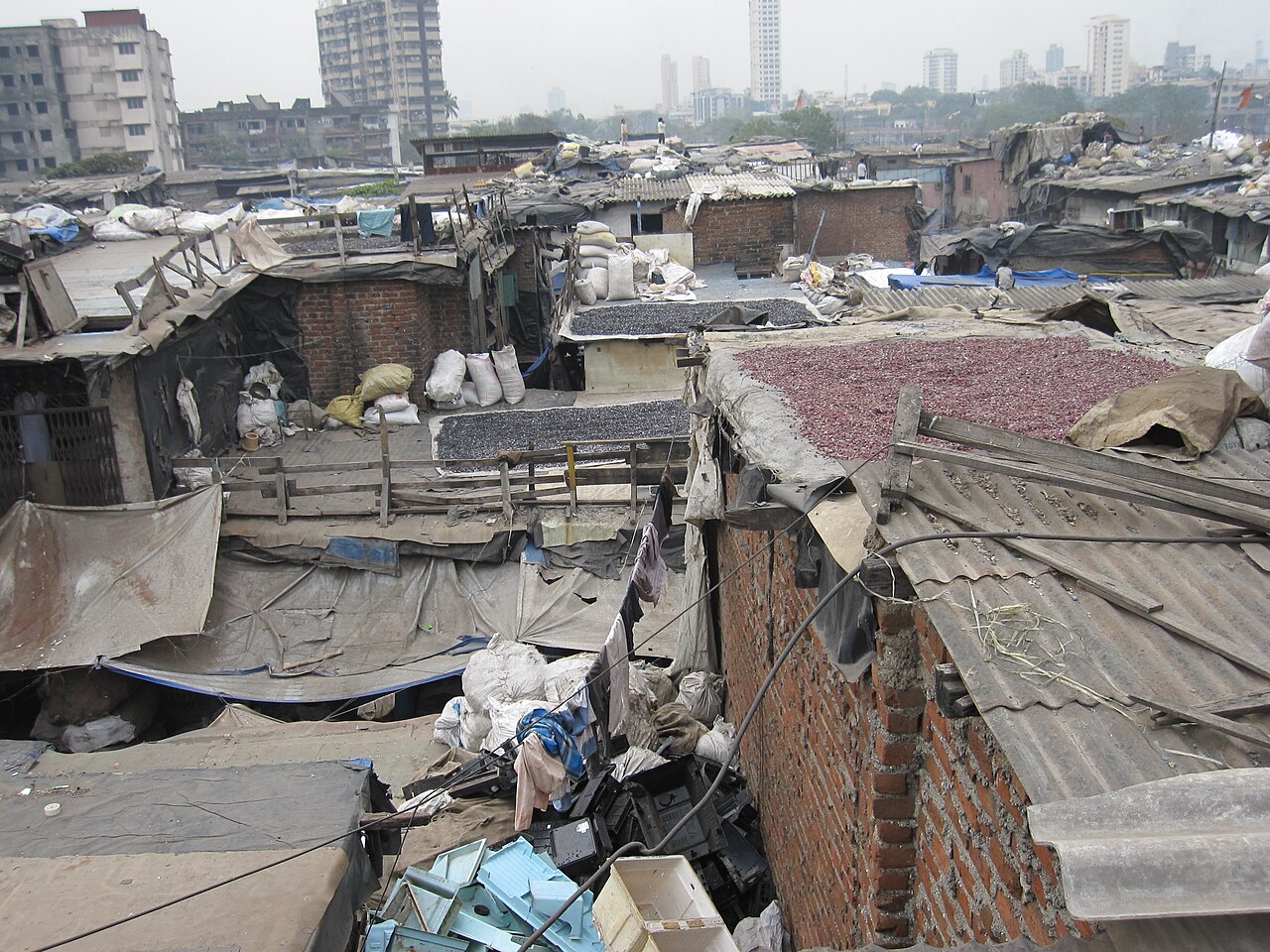 The rooftops of Dharavi slum in Mumbai, India, contrasted against high-rise buildings in the background