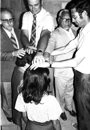 Black and white photograph of several men laying hands on a minister at an ordination