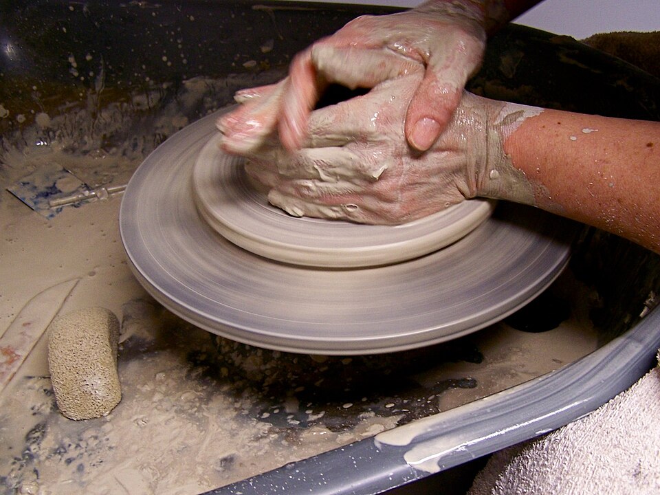 A potter’s hands shaping wet clay on a spinning wheel