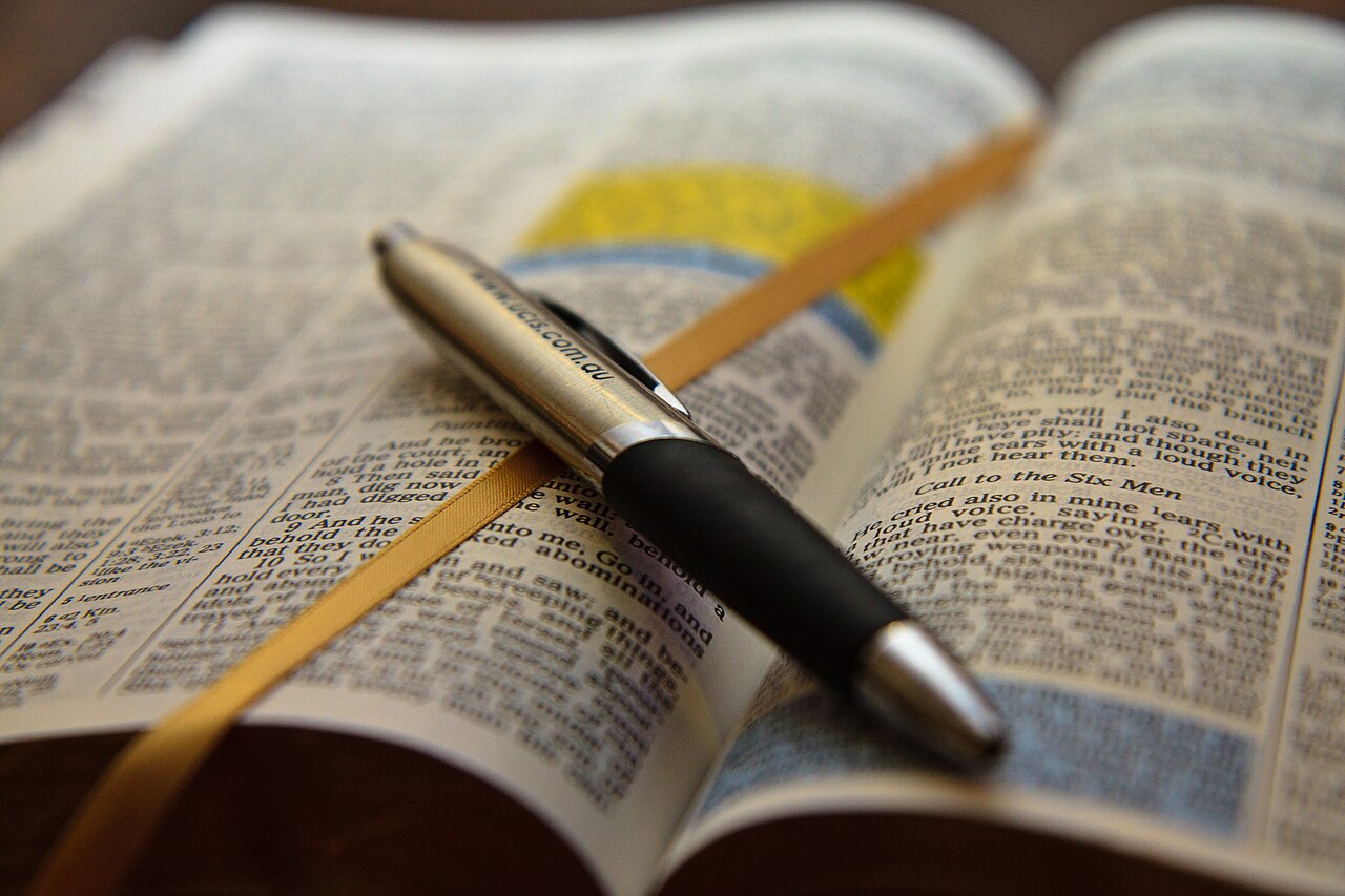 An open Bible and a pen, inviting time in the Word and a life offered to the Lord.