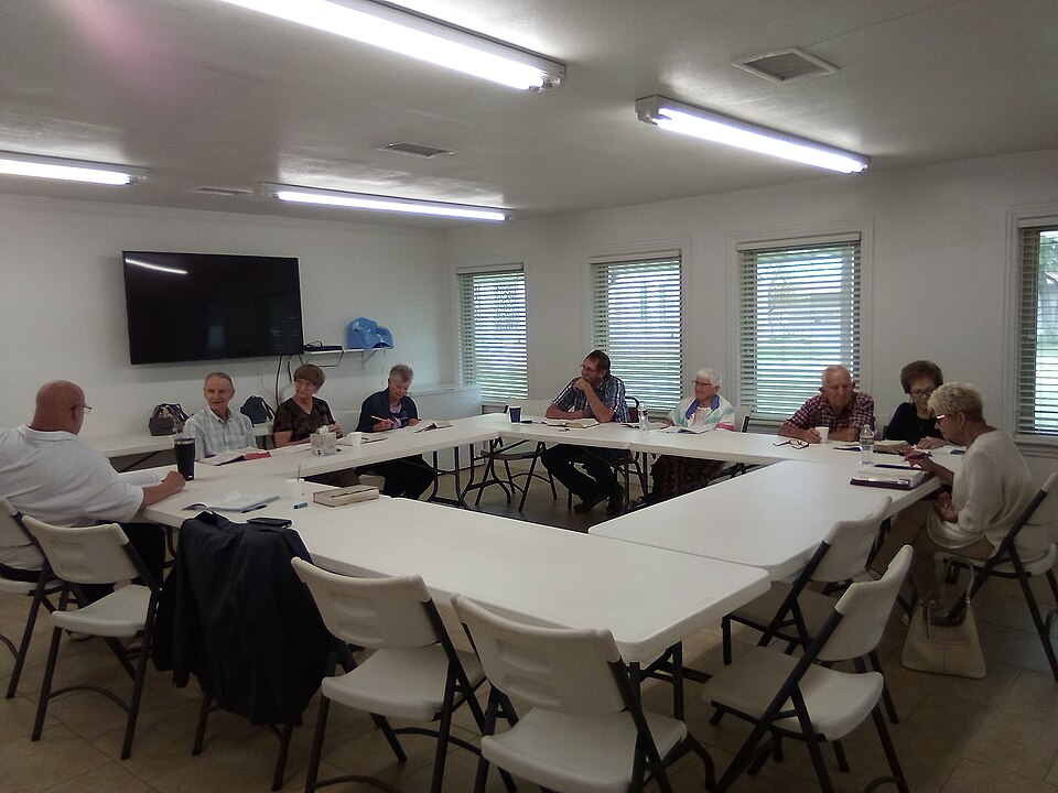 People seated around tables with open books at a church Bible study