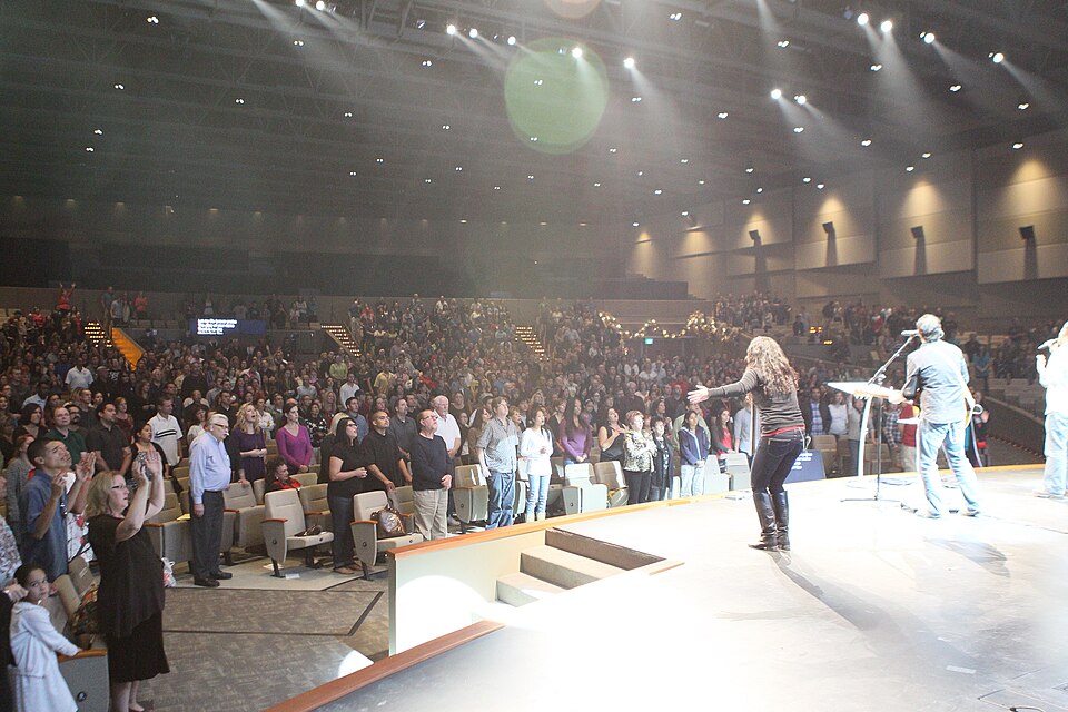 A standing congregation and leaders on stage during a worship service
