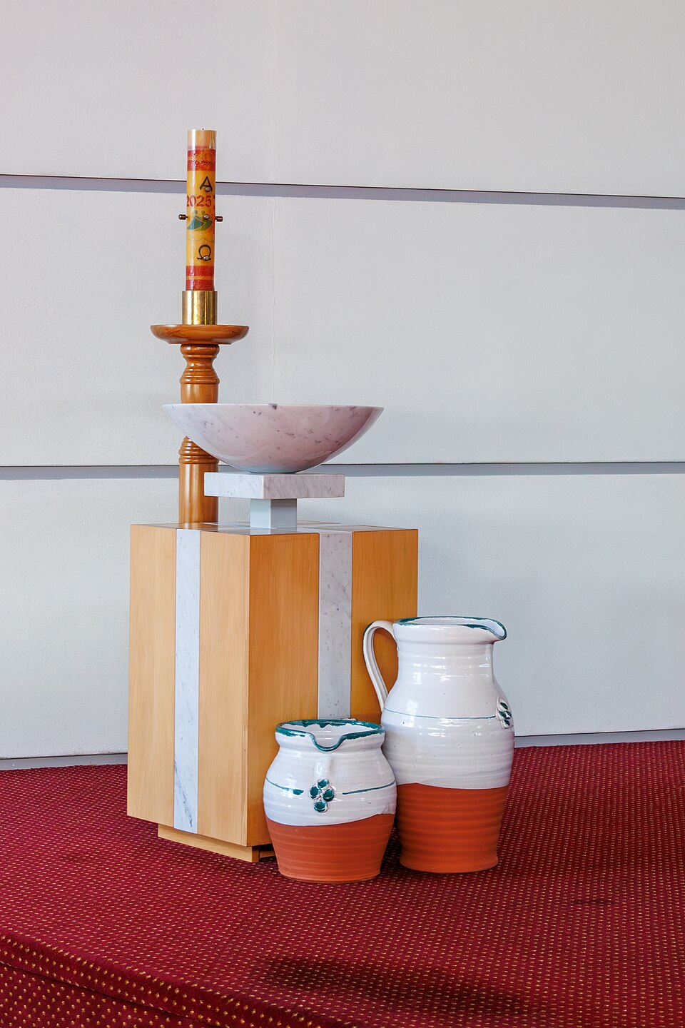 A baptismal font beside a candle, with two holy water containers below