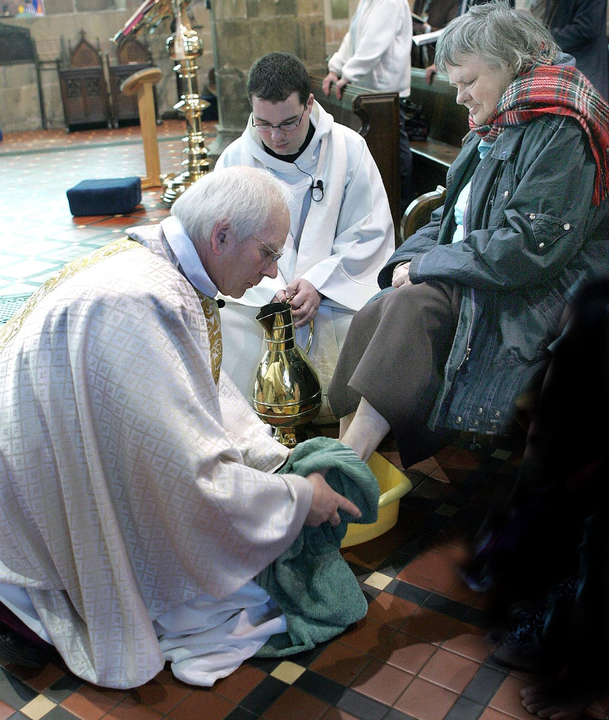 A clergyman washing another person’s feet during a modern church ceremony